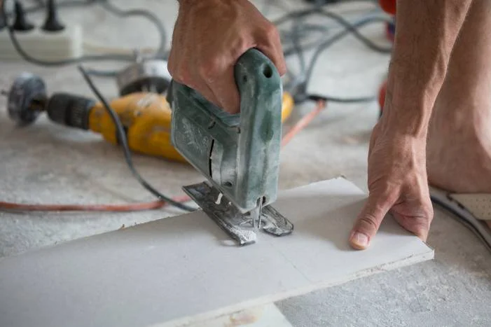 Person schneidet Rigipsplatte mit Stichsäge